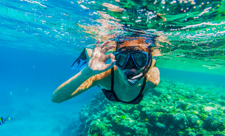 A woman enjoys snorkeling in the clear blue waters of Sri Lanka, giving an 'OK' sign.