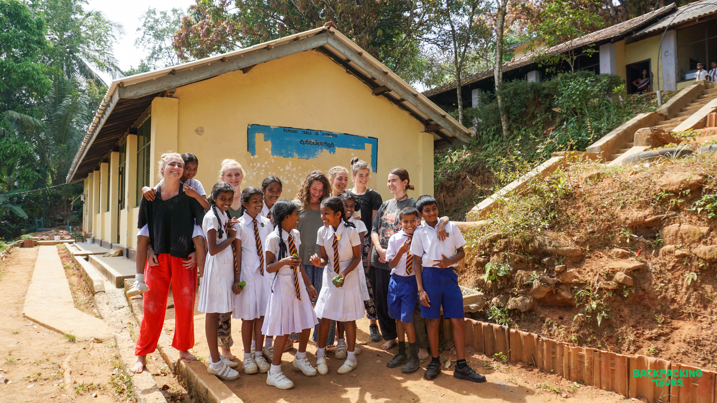 Happy volunteers and local children pose together outside a school building in rural Sri Lanka.