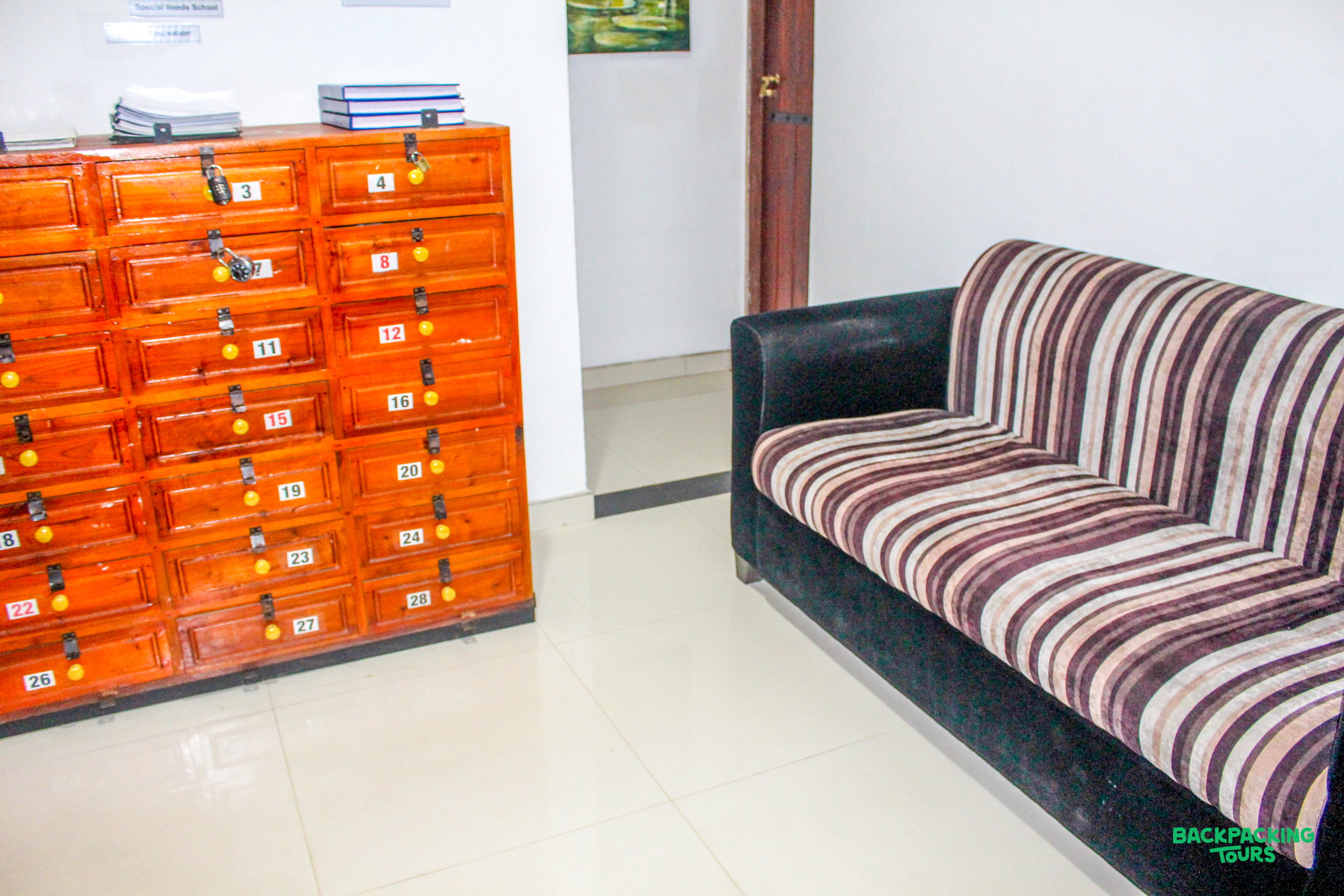 Striped sofa and wooden locker unit in a bright common room, part of your Sri Lankan accommodation.