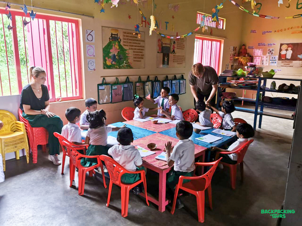 Volunteers engage with young students in a brightly decorated classroom in Sri Lanka.