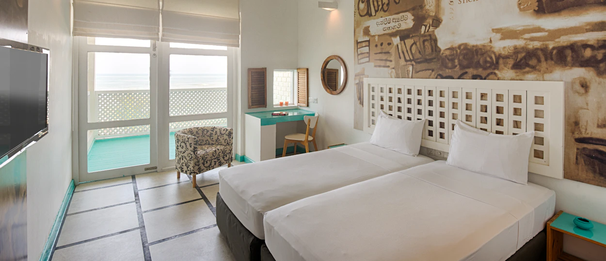 A bright hotel room with two single beds, a private plunge pool, and ocean views in Colombo.