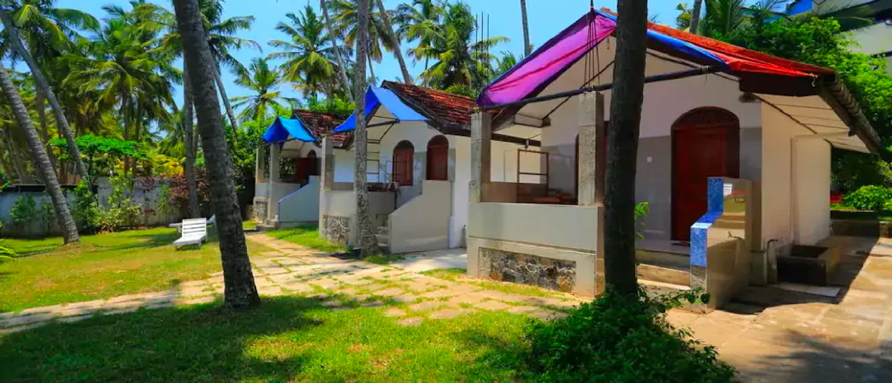 Relaxing bungalows with vibrant roofs under swaying palm trees in sunny Weligama, Sri Lanka.