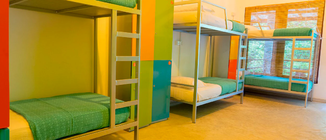 A bright and clean hostel dorm room with multiple bunk beds and colorful lockers in Sri Lanka.