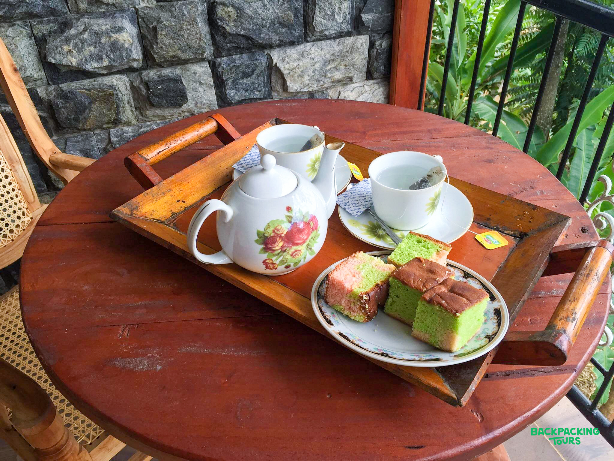 A delightful tea and cake spread on a wooden table on a balcony in Ella, Sri Lanka.