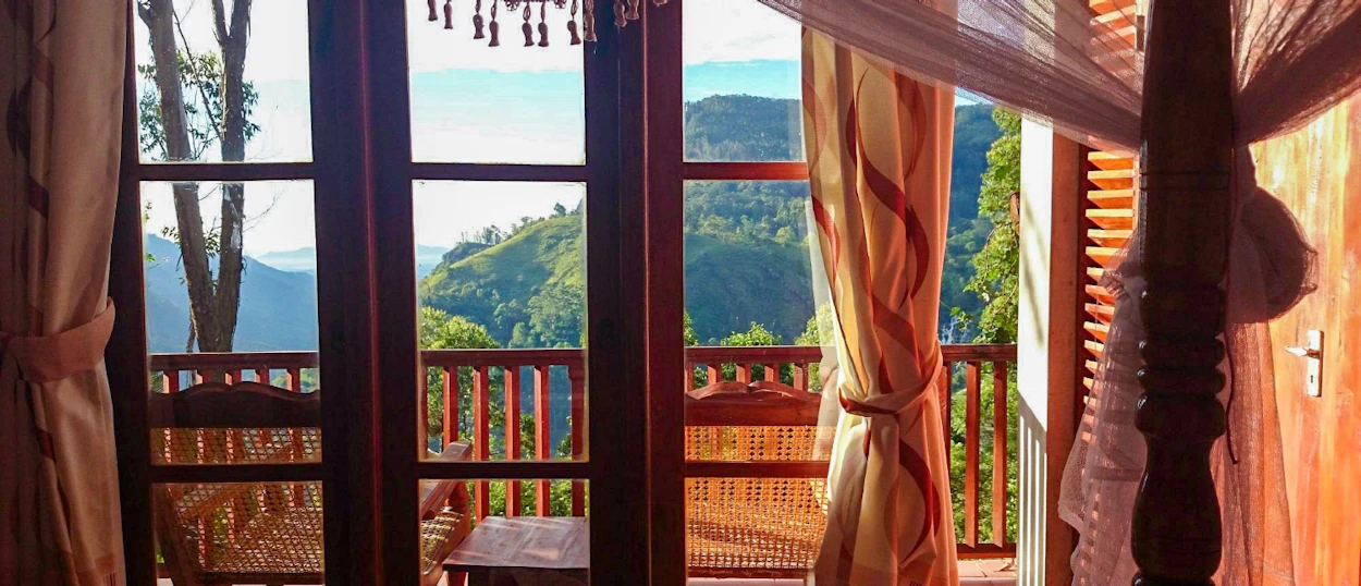 A cozy room with a balcony overlooking stunning green mountains and valleys in Ella, Sri Lanka.