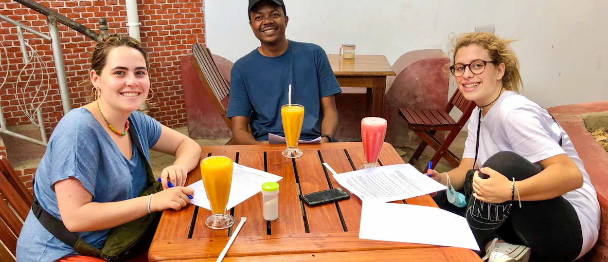 Three happy travelers enjoying tropical drinks and good company at a cafe in Zanzibar.