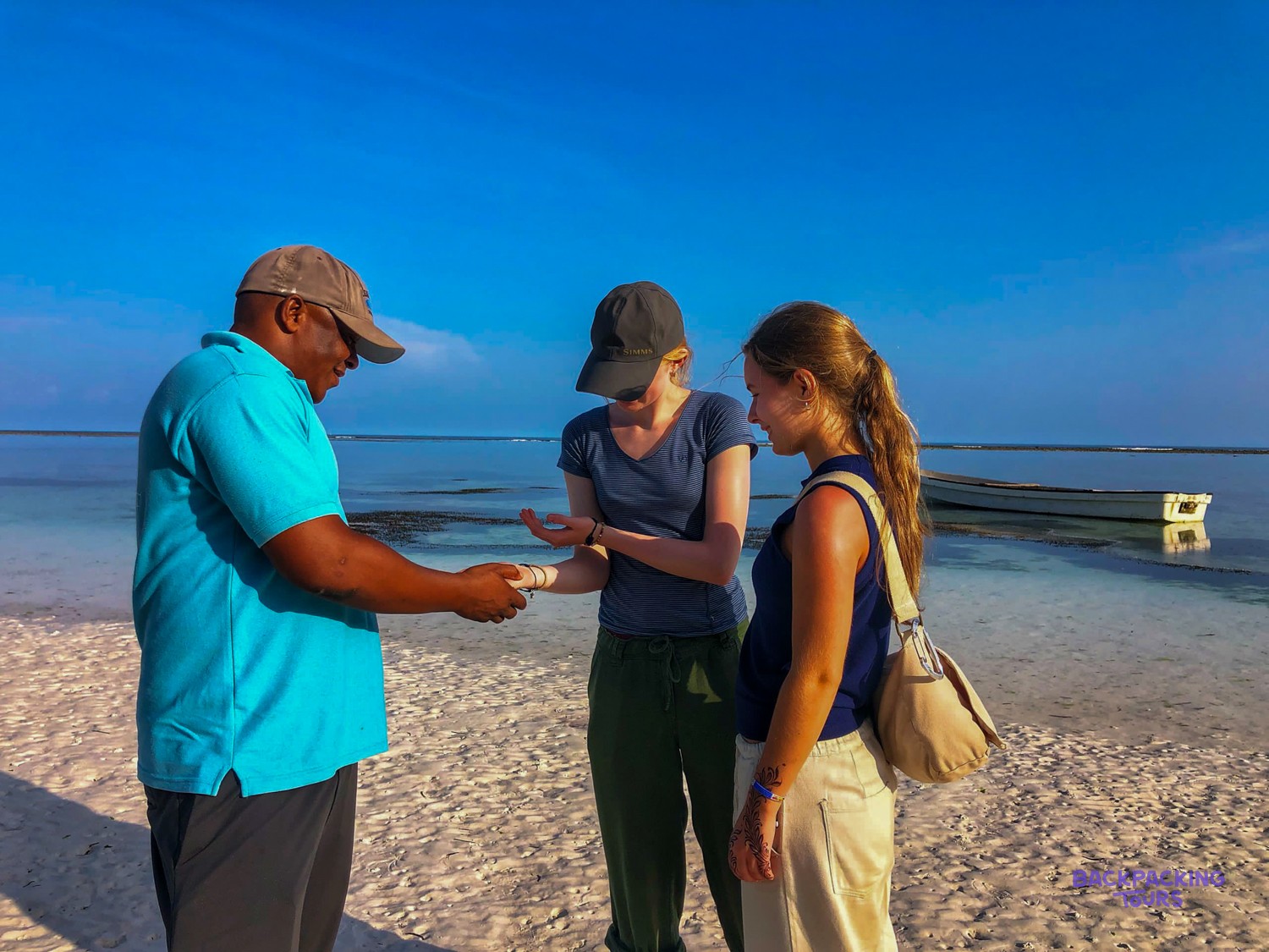A local guide shows two volunteers something he has picked up from the shore.