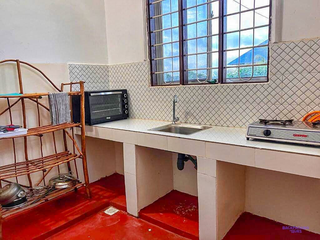 A tiled counter with a sink, a hotplate and a small oven fills the shared kitchen.