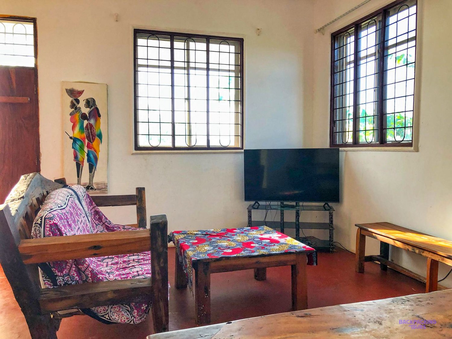 A wooden sofa, a low table and a television furnish the bright lounge of the house.