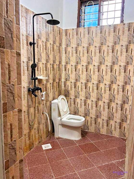 A tiled shower room with an overhead rose and a toilet in the corner.