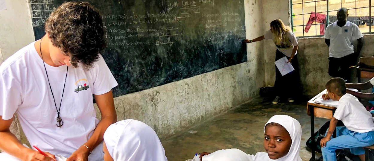 Volunteers teach and assist young students in a bright, busy classroom in Zanzibar.