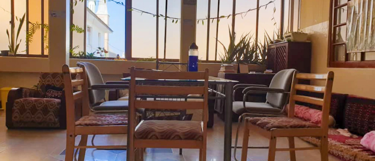 A welcoming common room with patterned chairs, a table, and floor cushions in Zanzibar.