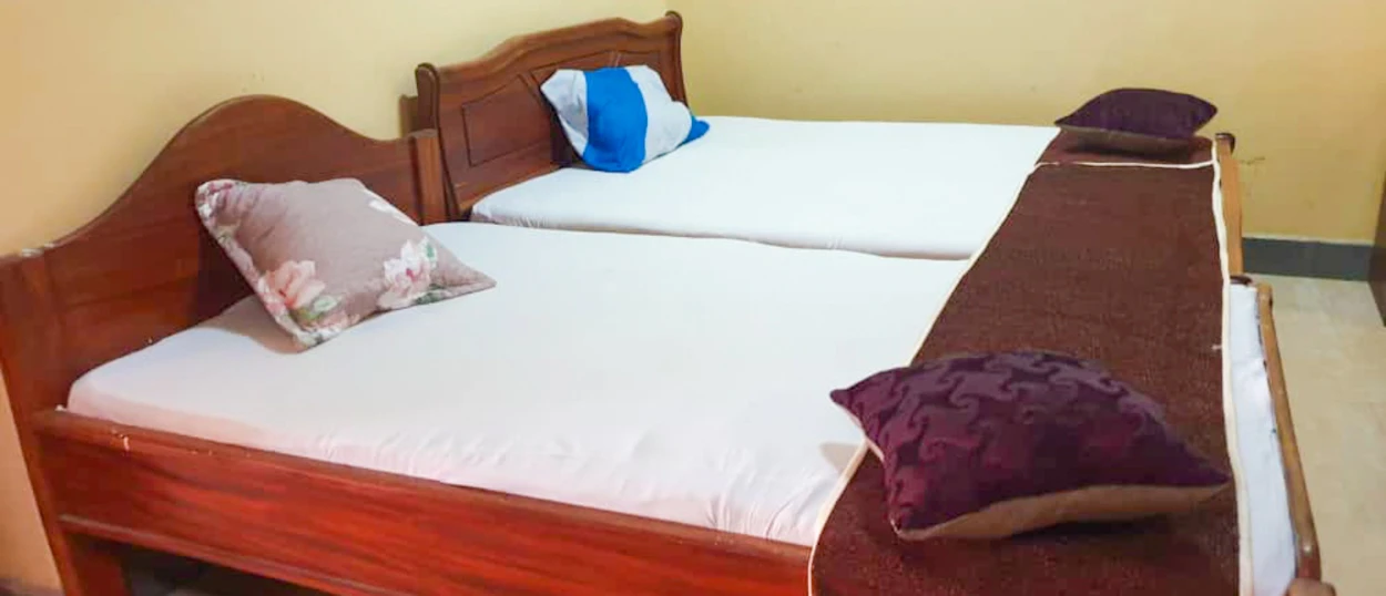 Simple and comfortable twin beds with white linens and decorative pillows in a Zanzibar accommodation.