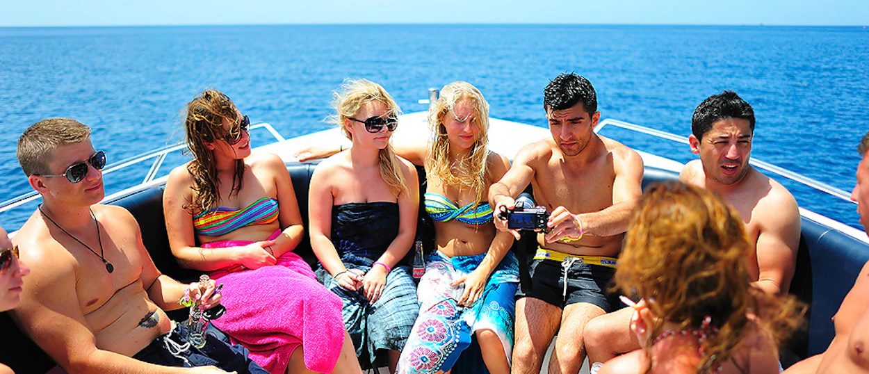 Young travelers relax on a boat, island hopping in the beautiful blue waters near Koh Tao.