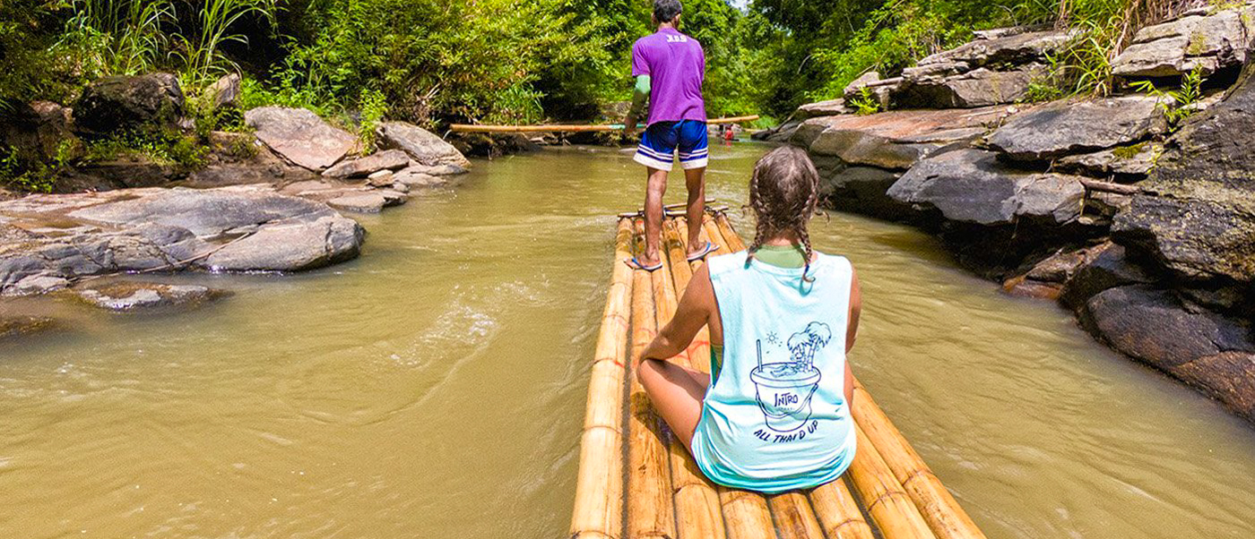 Backpacking tour participants bamboo rafting down a peaceful river in Chiang Mai
