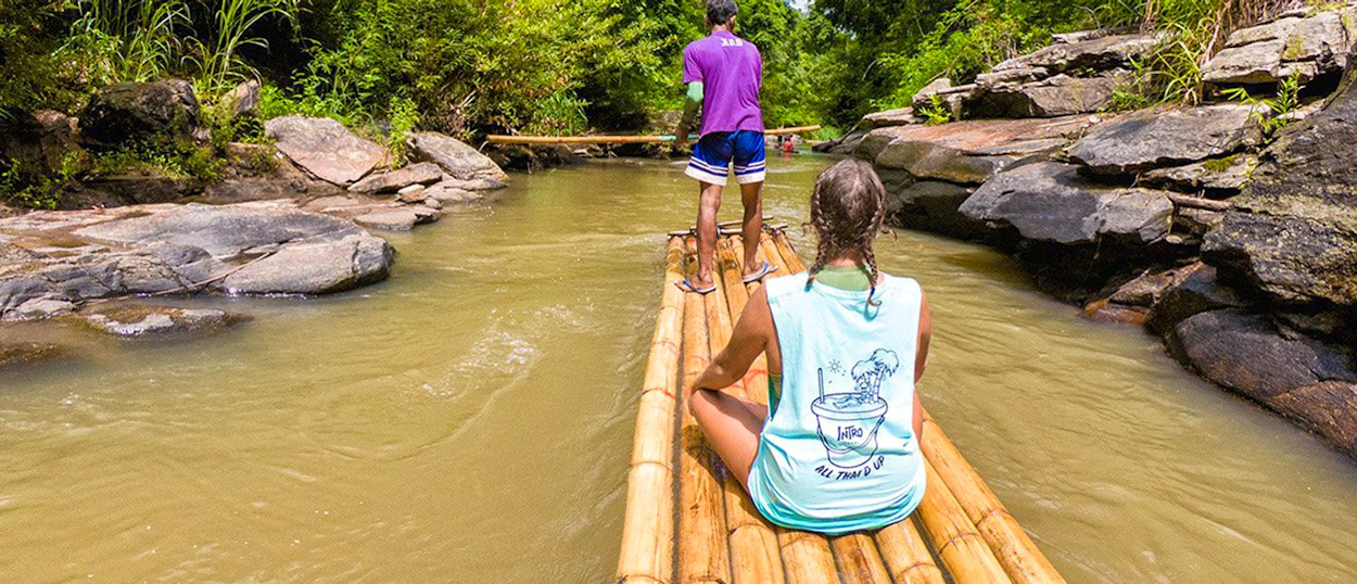 Two people enjoy a peaceful bamboo raft ride down a scenic river in Chiang Mai.