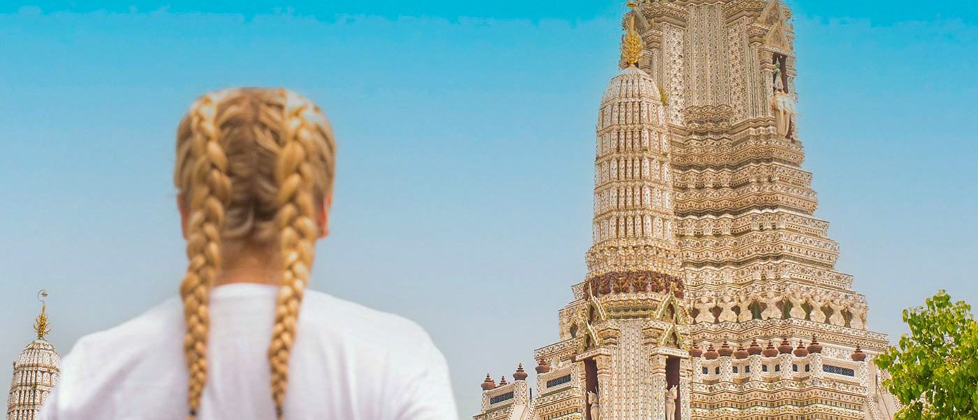 Backpacking tour group arriving in Bangkok, seeing temple skyline at sunset