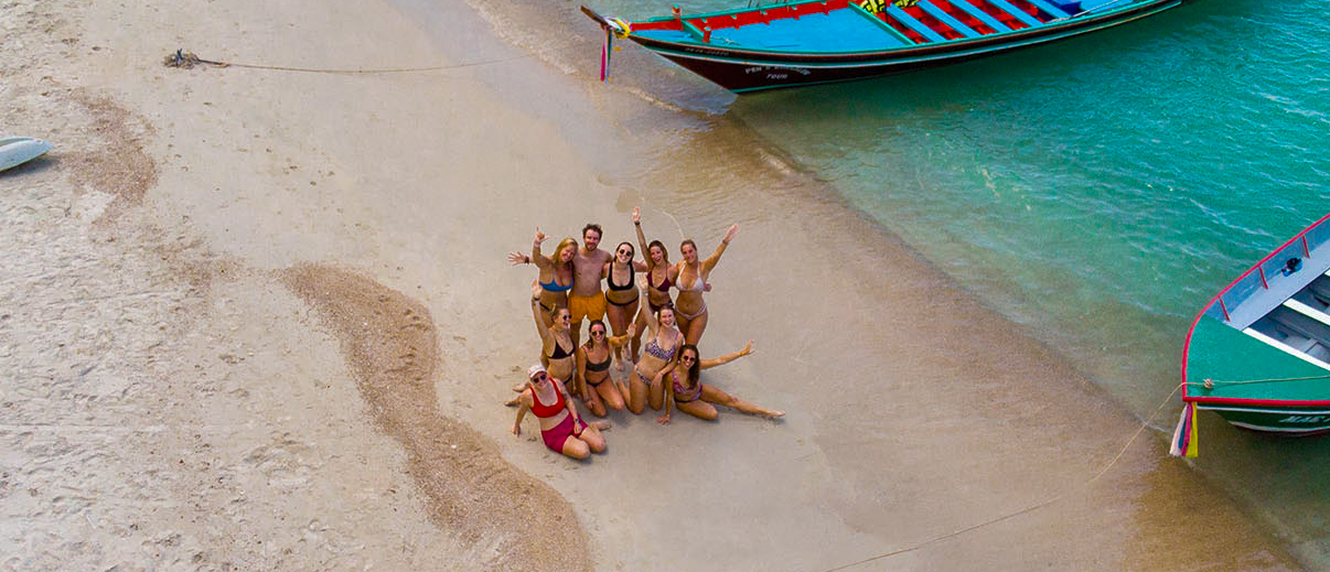 Drone shot of backpacking tour group arriving at Koh Phangan tropical beach on a boat