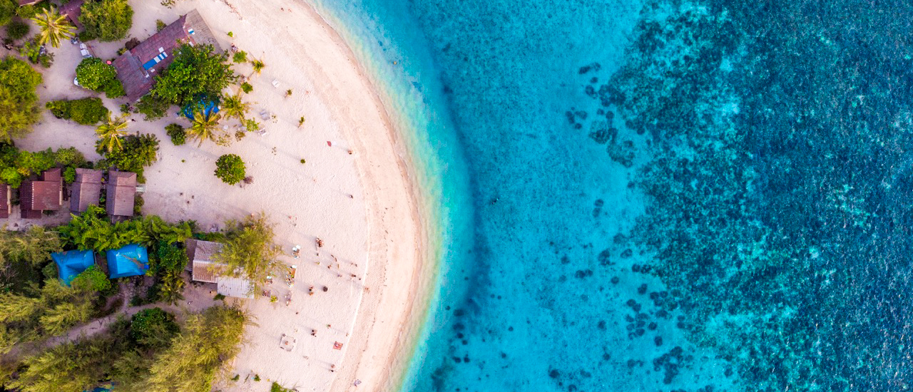 Aerial view of hidden beach and turquoise waters on Koh Phangan during island tour for backpacking groupBackpacking tour friends lying in a circle with outstretched arms on the sandy beach during island tour