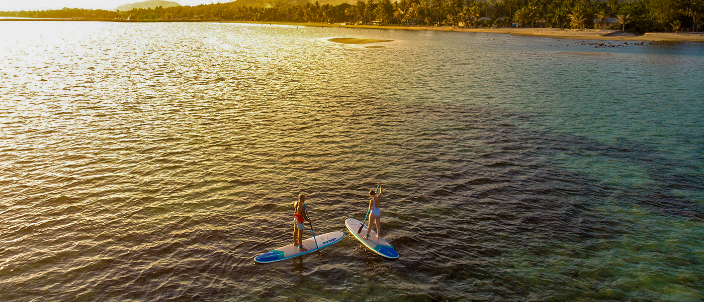 Backpacking tour participant paddleboarding at sunset on calm sea in Koh Phangan