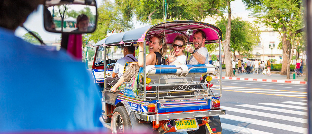 Colorful tuk tuk ride through Bangkok with backpacking tour group exploring temples
