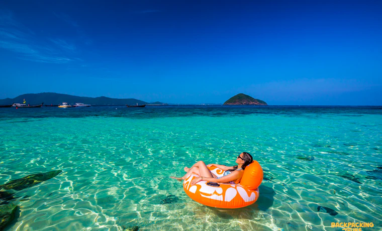 Relaxing on an orange float in the clear turquoise waters of Phuket under a bright blue sky.