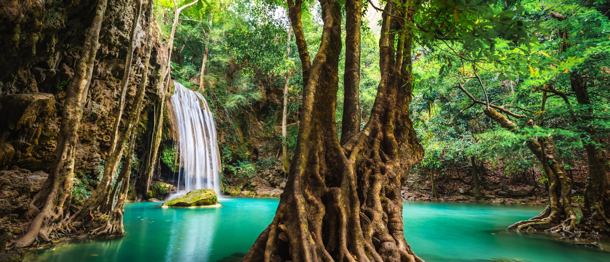 Emerald green pools at Erawan Waterfalls, with a waterfall cascading through lush jungle.