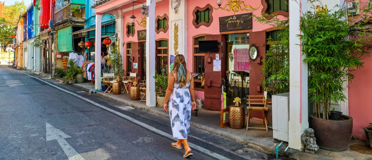 A woman with blue streaked hair walks past colourful Sino-Portuguese shophouses in Phuket Old Town.