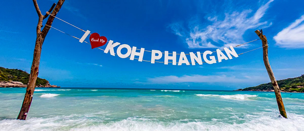 A handmade 'I love Koh Phangan' sign overlooks a beautiful tropical beach with turquoise water.