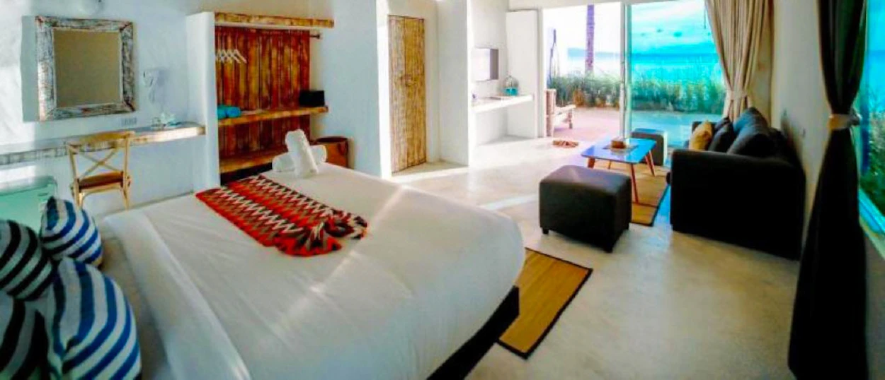Bright hotel room with a bed, seating area, and patio overlooking the ocean on Koh Phangan.