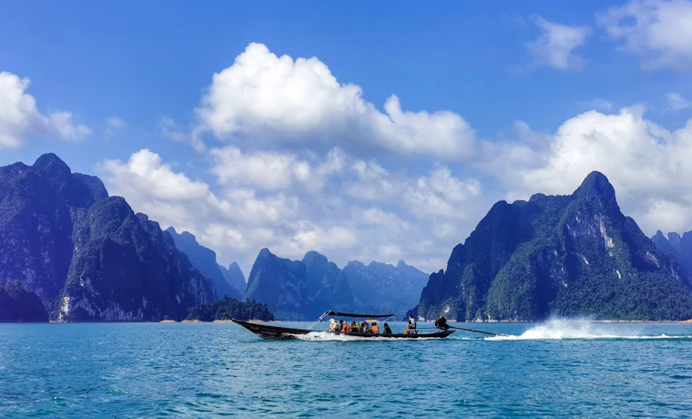 Tourists enjoy a scenic longtail boat ride through the majestic limestone karsts of Khao Sok National Park.
