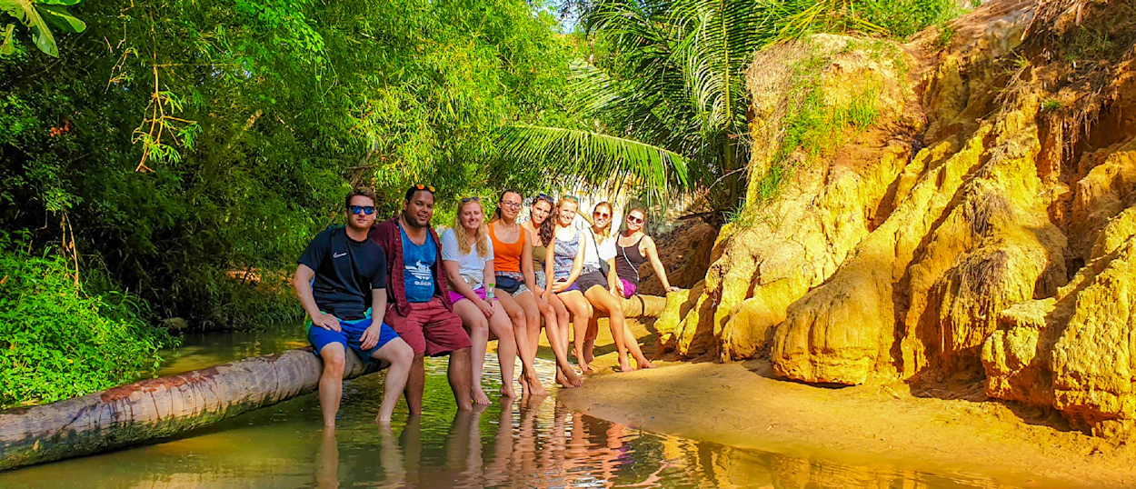 A group of happy backpackers relax with their feet in the water at Vietnam's enchanting Fairy Stream.