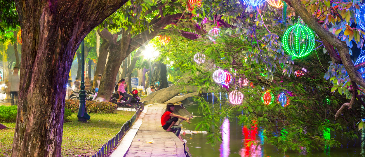 People enjoy a vibrant night in a Hanoi park, illuminated by many colorful lanterns.