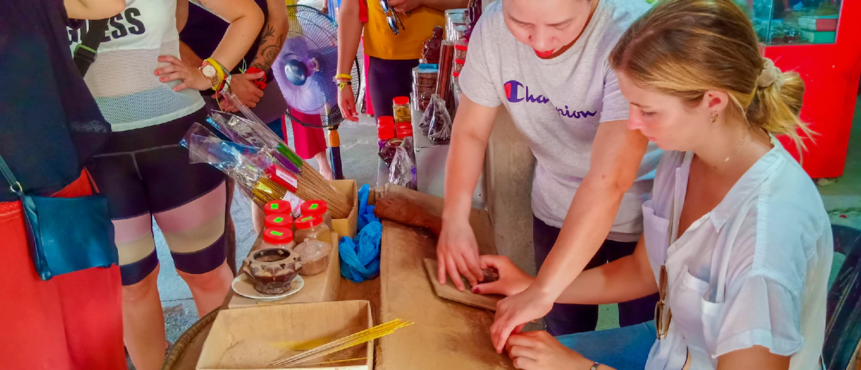 Two travelers learn to make traditional incense sticks at a workshop in Hue.