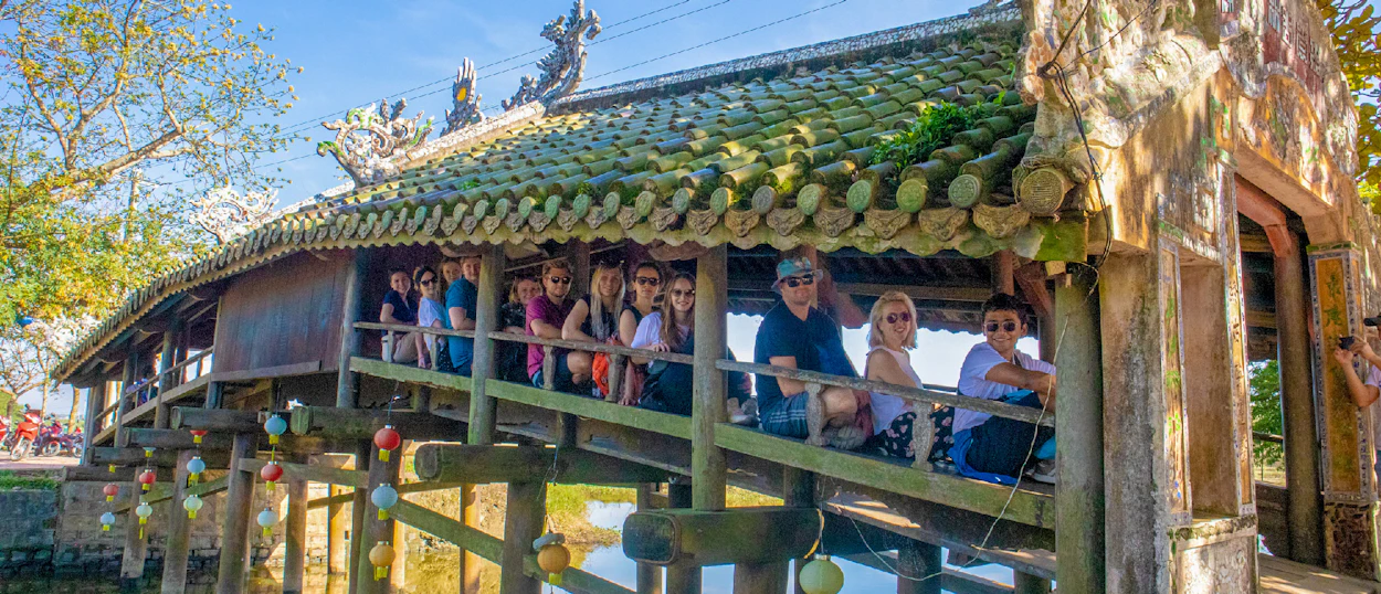 A group of tourists enjoying the view from the historic Japanese Covered Bridge in Hoi An.