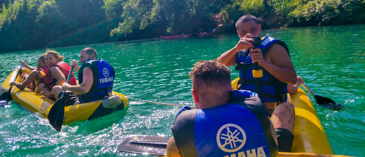 Adventurous travelers kayak on a beautiful green river in Phong Nha, enjoying the sunny day.