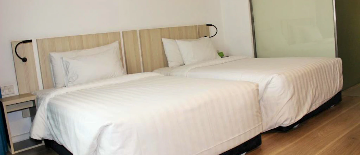 A comfortable, modern hotel room featuring two single beds with crisp white linen.