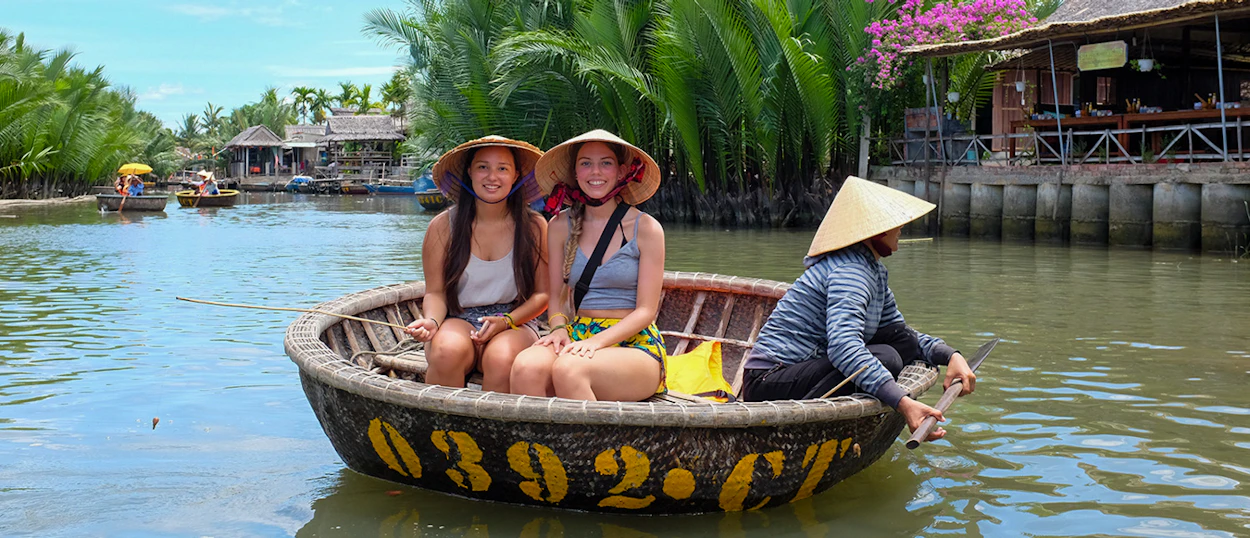Tourists enjoy a scenic basket boat ride with a local paddler on the river in Hoi An.