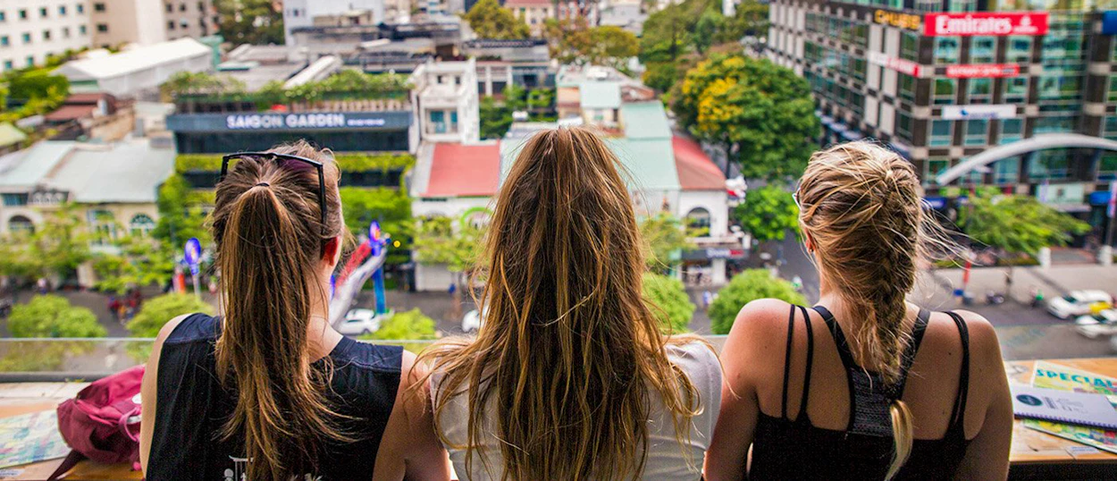 Three women gaze from a rooftop over the bustling city of Ho Chi Minh.