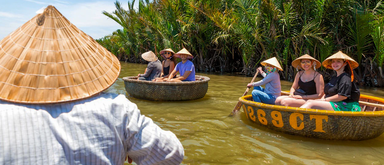 Tourists and local guides enjoy a basket boat ride through palm groves in Hoi An, Vietnam.