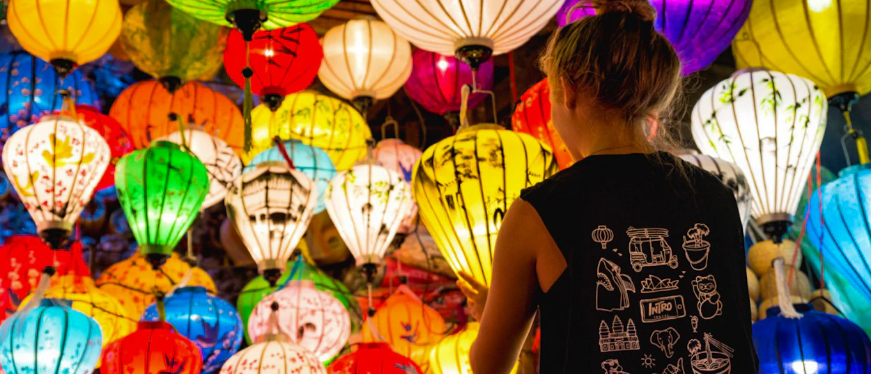 A person views a vibrant display of many glowing, colorful traditional lanterns in Hoi An.