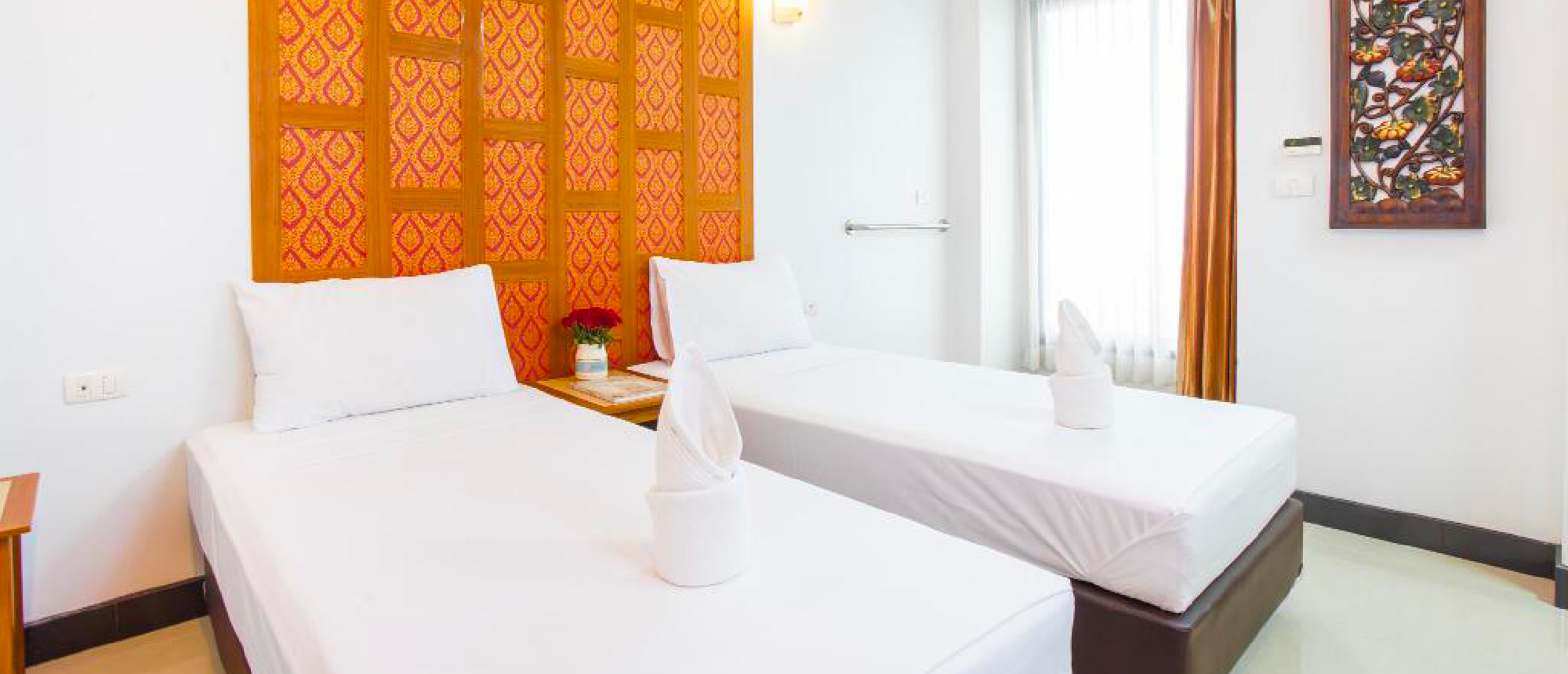 Modern hotel room with two single beds and an orange headboard in Bangkok